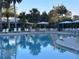 Inviting community pool with ample seating, umbrellas, and palm trees creating a relaxing resort-style atmosphere at 3817 Miragalia Ln, The Villages, FL 32163
