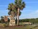 The Hammock golf course sign made of stone and natural materials amongst palm trees, blue sky and green grass at 3817 Miragalia Ln, The Villages, FL 32163