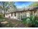 Exterior corner of a home with a stucco finish, showcasing a garden hose, and lush foliage at 3930 Griffin Ave, Lady Lake, FL 32159