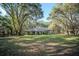 Estate's exterior showcases a lush, expansive yard and mature trees providing ample shade and privacy at 3930 Griffin Ave, Lady Lake, FL 32159