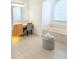 Bright bathroom features a vanity with a makeup area, an ottoman, and a soaking tub beneath a window at 3969 Derby Glen Dr, Clermont, FL 34711