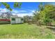 Green backyard featuring a shed, firepit, and a fenced area, offering plenty of space for outdoor activities at 410 E Gulley Ave, Oakland, FL 34760