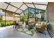 Inviting sunroom featuring wicker furniture, a patterned rug, and an outdoor view with mature trees at 410 E Gulley Ave, Oakland, FL 34760