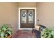 Inviting double front doors with decorative wreaths, a charming bench, and vibrant potted plants on a brick porch at 440 Bellissimo Pl, Howey In The Hills, FL 34737