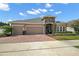 Beautiful exterior of home with a paver driveway, three-car garage, and manicured landscaping at 440 Bellissimo Pl, Howey In The Hills, FL 34737