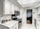 Bright kitchen featuring white cabinets, stainless steel appliances, marble countertops, and an inviting doorway at 500 Newell Hill Rd # 113D, Leesburg, FL 34748