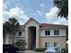 A two-story building with a tile roof and tan exterior features a welcoming entrance and mature landscaping at 508 Villa Del Sol Cir # 105, Orlando, FL 32824