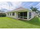 Rear exterior view showcasing the home's well-maintained lawn, screened-in porch, and neutral-colored facade at 541 Cokesbury Dr, The Villages, FL 32162