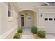 Inviting front entrance featuring a covered porch, lovely door with wreath, and manicured bushes at 541 Cokesbury Dr, The Villages, FL 32162