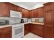 Compact kitchen with wood cabinetry, white appliances and a gas range at 541 Cokesbury Dr, The Villages, FL 32162