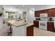 Well-lit kitchen with a breakfast bar, wood cabinets, tile flooring, and direct view into the dining area at 541 Cokesbury Dr, The Villages, FL 32162