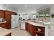 Spacious kitchen with wood cabinets, white appliances, and a breakfast bar overlooking the living area at 541 Cokesbury Dr, The Villages, FL 32162