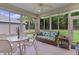 Bright sunroom featuring tile flooring, wicker furniture, and large windows with views of the lush outdoors at 541 Cokesbury Dr, The Villages, FL 32162
