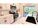 Modern kitchen with white cabinets, stainless steel appliances, and a view to a patio at 591 Black Eagle Dr, Groveland, FL 34736