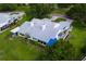 Aerial view features blue accents, lush landscaping, mature trees, and a tile roof at 6048 Topsail Rd, Lady Lake, FL 32159