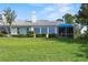 View of a lush green backyard with large windows and a screened-in patio for indoor/outdoor living at 6048 Topsail Rd, Lady Lake, FL 32159
