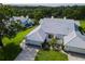 Stunning aerial view of a well-maintained home featuring a blue tile roof, green lawn, and mature trees at 6048 Topsail Rd, Lady Lake, FL 32159