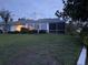Back exterior view of a home featuring a screen porch, lush lawn, and a well-kept garden at 6048 Topsail Rd, Lady Lake, FL 32159