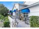 Charming exterior featuring blue awnings, a serene patio, and lush, manicured greenery at 6048 Topsail Rd, Lady Lake, FL 32159