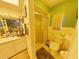 A full bathroom with standing shower, white toilet, and vanity sink, all in yellow and green colors at 6221 Ambassador Dr, Orlando, FL 32808