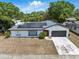 Charming single-story home with a spacious driveway, lush landscaping, and solar panels for energy efficiency at 6221 Ambassador Dr, Orlando, FL 32808