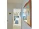 Hallway with view into kitchen, light walls, neutral tile flooring, mirror and artwork at 6221 Ambassador Dr, Orlando, FL 32808