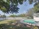 Backyard view of a pool, surrounded by white vinyl fence, grass, and greenery at 6221 Ambassador Dr, Orlando, FL 32808