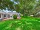Backyard view featuring a screened-in pool area, manicured lawn, and mature trees, perfect for relaxing at 628 San Pedro Dr, The Villages, FL 32159