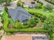 Aerial view of a home with screened lanai, manicured backyard landscaping, and lush green surroundings at 654 Poinsett Ct, The Villages, FL 32162