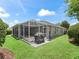 A spacious backyard showcasing a screened patio with grill, a gray exterior, and well-maintained green lawn at 654 Poinsett Ct, The Villages, FL 32162