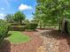 Backyard landscaping featuring river rock, mulch and neatly trimmed hedges and trees in a verdant setting at 654 Poinsett Ct, The Villages, FL 32162