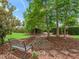 A serene backyard with a rock garden and bench surrounded by mature trees and lush landscaping at 654 Poinsett Ct, The Villages, FL 32162