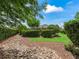 View of the impeccably landscaped backyard, featuring mulch, rocks, and perfectly trimmed hedges at 654 Poinsett Ct, The Villages, FL 32162