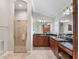 This renovated bathroom features dual sinks, granite counters, and a glass enclosed shower at 654 Poinsett Ct, The Villages, FL 32162