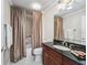 Elegant bathroom featuring dark wood vanity, granite countertop, and tiled shower with a shower curtain at 654 Poinsett Ct, The Villages, FL 32162