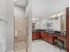 This renovated bathroom features dual sinks, granite counters, and a glass enclosed shower at 654 Poinsett Ct, The Villages, FL 32162