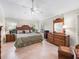 Spacious bedroom with decorative wicker headboard, tiled floors, ceiling fan, and a large dresser at 654 Poinsett Ct, The Villages, FL 32162