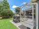 View of the patio with a grill and an outdoor dining area overlooking the manicured lawn at 654 Poinsett Ct, The Villages, FL 32162
