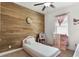 Bright bedroom with light pink furniture, a wood accent wall, and a ceiling fan at 686 Black Eagle Dr, Groveland, FL 34736