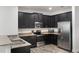 Modern kitchen featuring dark cabinetry, granite countertops, stainless steel appliances, and wood-look tile flooring at 686 Black Eagle Dr, Groveland, FL 34736