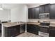 Modern kitchen featuring dark cabinets, stainless steel appliances, and granite countertops, seamlessly connecting to the dining area at 686 Black Eagle Dr, Groveland, FL 34736