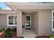 Inviting front entry featuring a covered porch, neutral paint, and manicured landscaping at 7162 Se 124Th St, Belleview, FL 34420