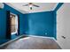 Bedroom featuring vibrant blue walls, carpeted flooring, and a window with dark curtains at 9220 San Jose Blvd, Howey In The Hills, FL 34737
