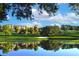Scenic golf course view with a serene lake reflecting the resort and palm trees, creating a picturesque landscape at 9220 San Jose Blvd, Howey In The Hills, FL 34737