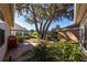 An outdoor patio in a lush garden setting is shaded by a large tree at 9430 Se 176Th Saffold St, The Villages, FL 32162