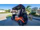Rear view of an orange golf cart parked in the driveway at 9430 Se 176Th Saffold St, The Villages, FL 32162