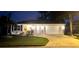 Charming single-story home with a well-manicured lawn, illuminated by exterior lights at dusk at 9430 Se 176Th Saffold St, The Villages, FL 32162
