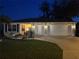 Home with a landscaped lawn and illuminated exterior, featuring a two-car garage at twilight at 9430 Se 176Th Saffold St, The Villages, FL 32162