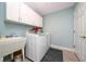Clean laundry room with washer, dryer, utility sink, and ample storage cabinets at 9430 Se 176Th Saffold St, The Villages, FL 32162