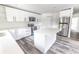 Modern kitchen boasts sleek white cabinetry, a large island with quartz countertops, and stainless steel appliances at Lot 21 Indian Estates Cr 423, Lake Panasoffkee, FL 33538